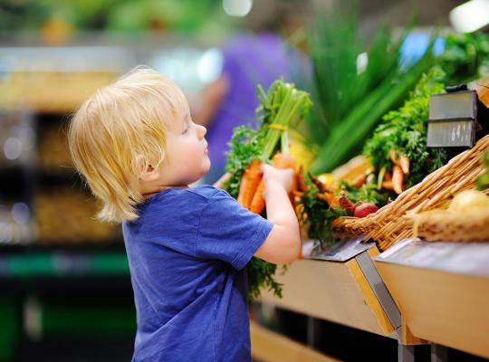 Kind neemt wortelen in supermarkt